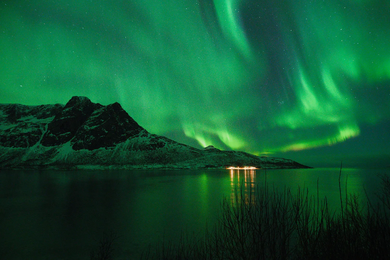 Northern lights over a mountain, reflected in still water