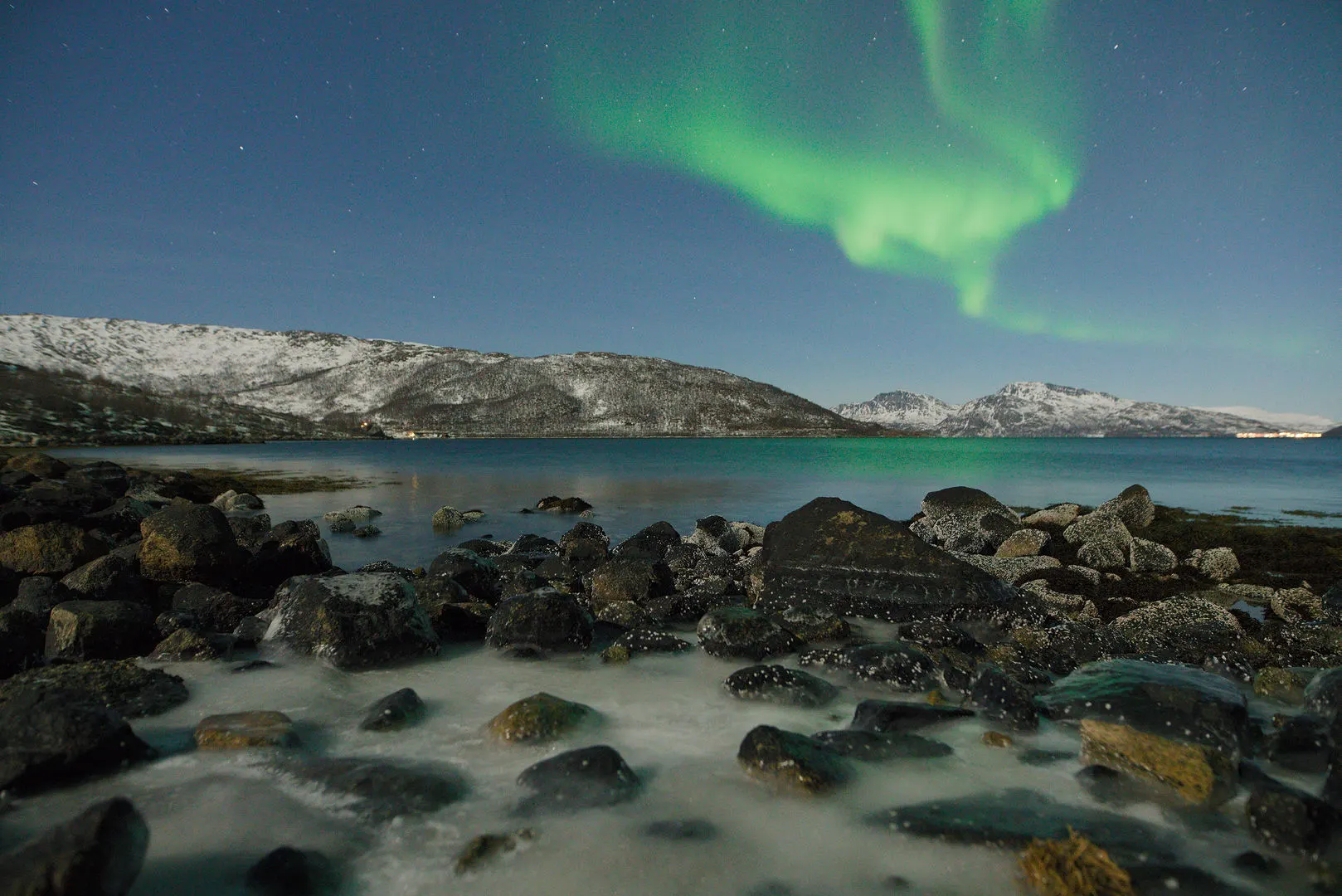 Northern lights over a rocky shore near Nordkjosbotn