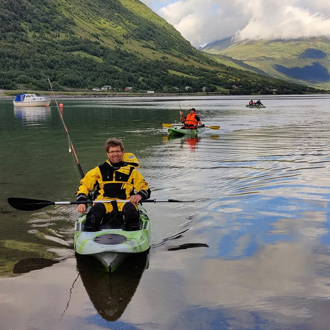 A guest paddling a sit-on-top kayak on a calm fjord