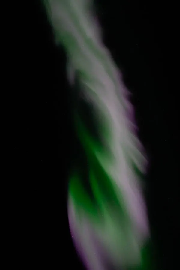 A twisting ribbon of green and pink aurora
