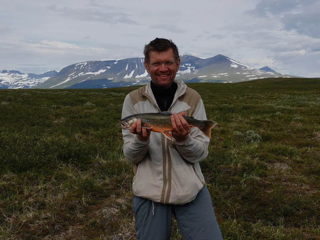 Roy holding a freshly caught trout on the summer tundra